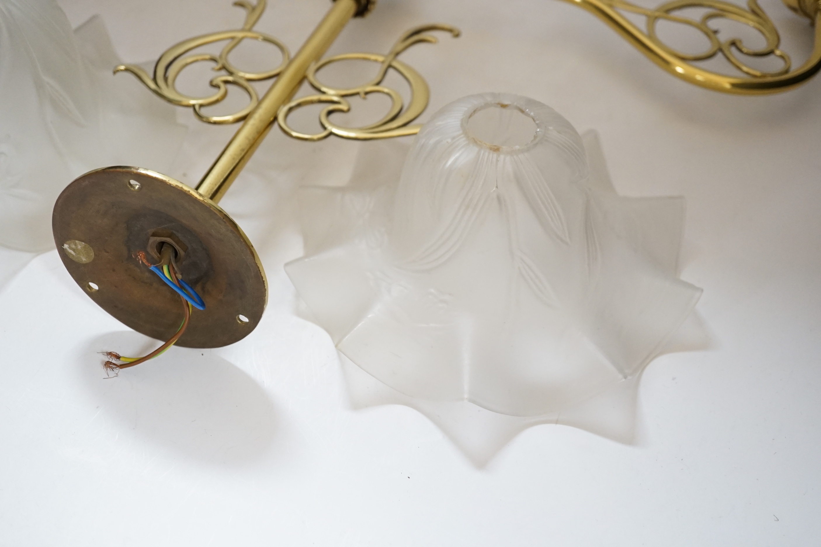 A brass pendant light and two opaque glass frilled shades, 60cm wide